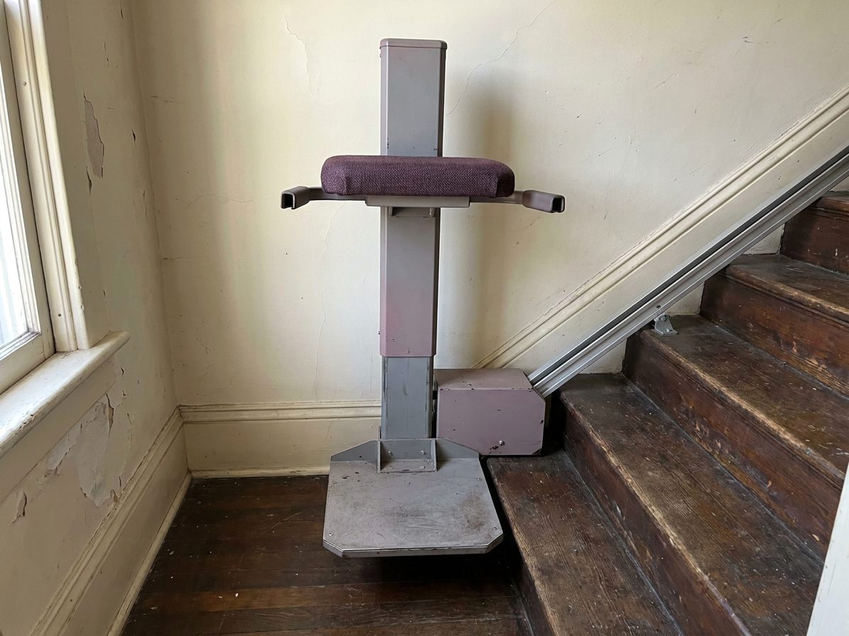 Standing stair elevator with a small perch seat on a narrow staircase