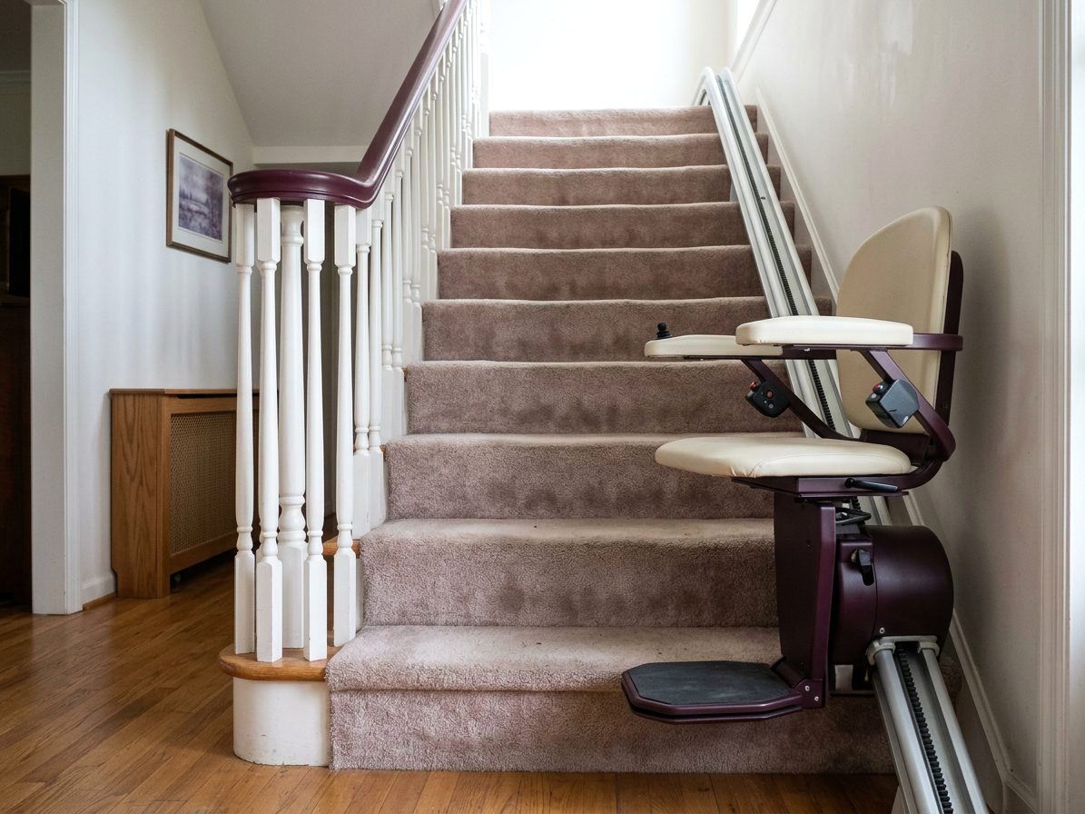 Stair elevator parked at the foot of a straight carpeted staircase